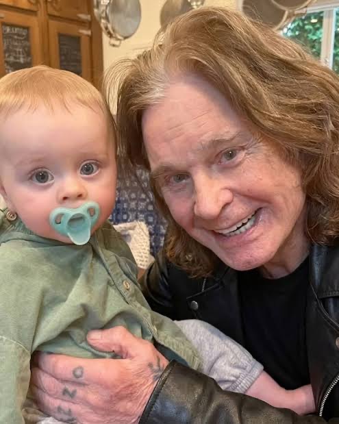 Ozzy Osbourne smiled warmly while holding his baby grandson Sidney in a sweet family photograph, capturing one of the precious moments they shared before the rock legend's death. | Source: Instagram/@kellyosbourne