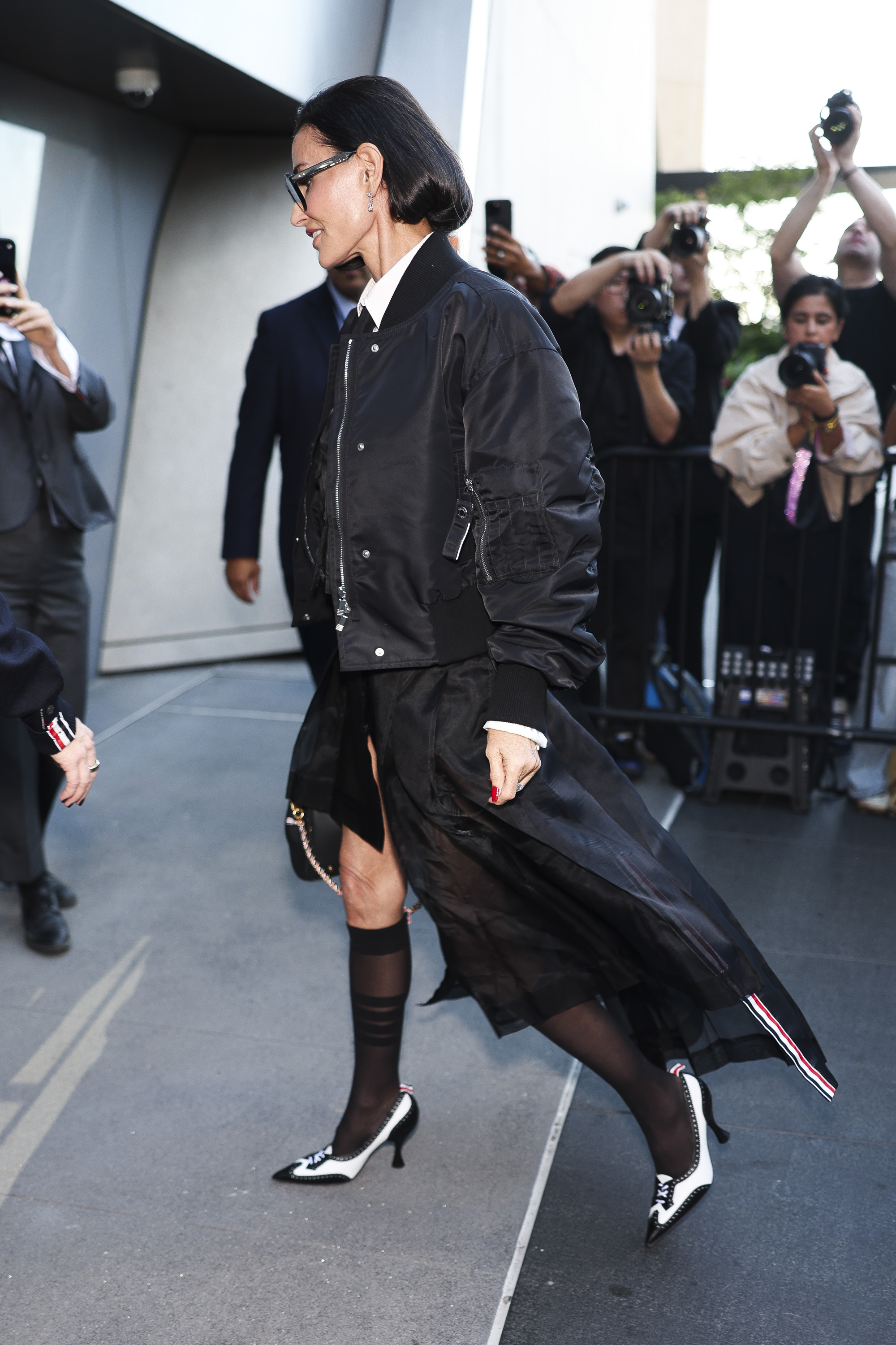 Demi Moore gives a side view of her sharply styled bob as she arrives at Thom Browne's New York Fashion Week show in a layered black ensemble, finished with sheer knee-high socks and black-and-white heels. | Source: Getty Images