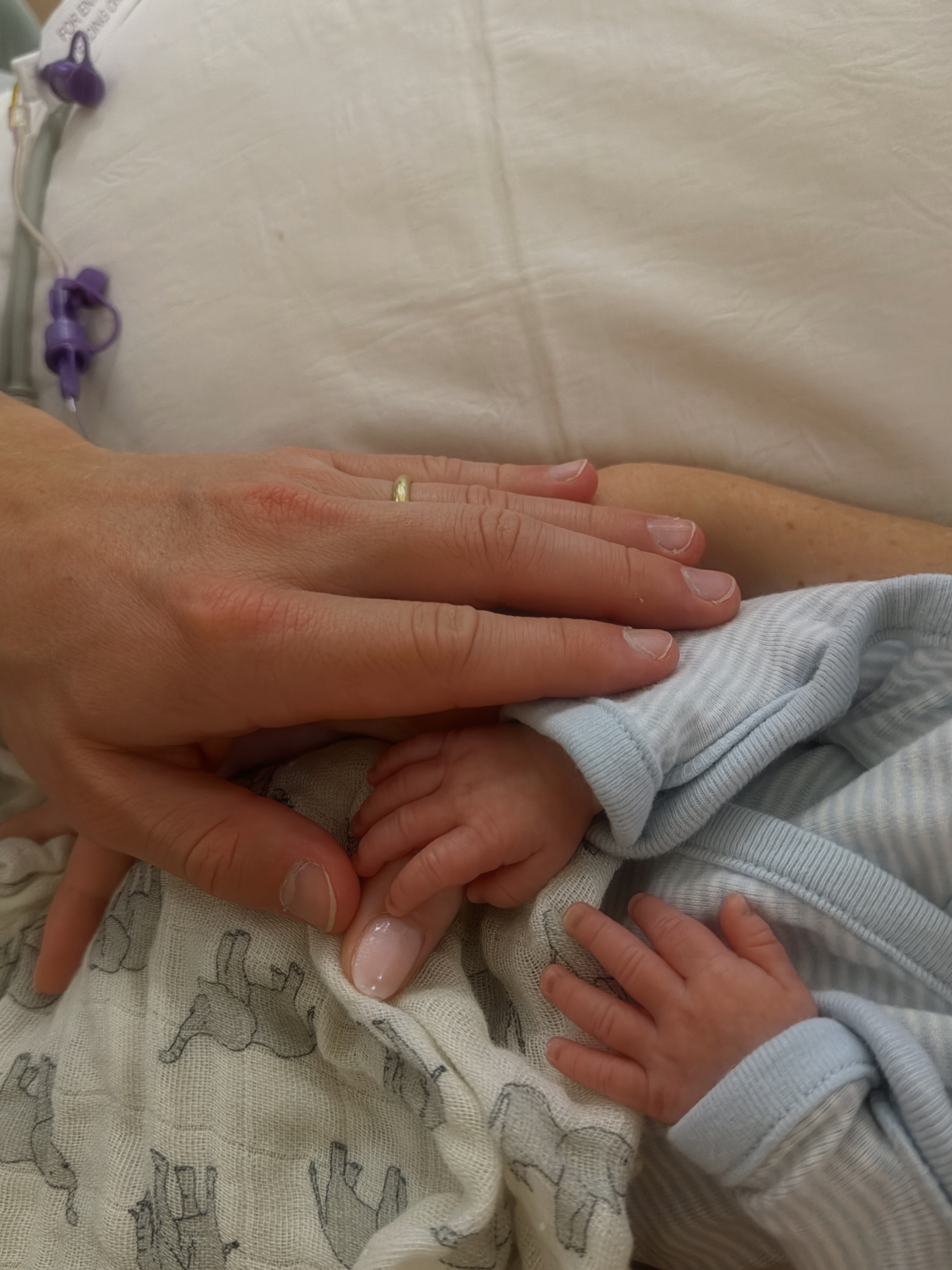 Bond's tiny hand rests beneath those of his parents in a close-up hospital photo, capturing the striking difference in size during his early days.