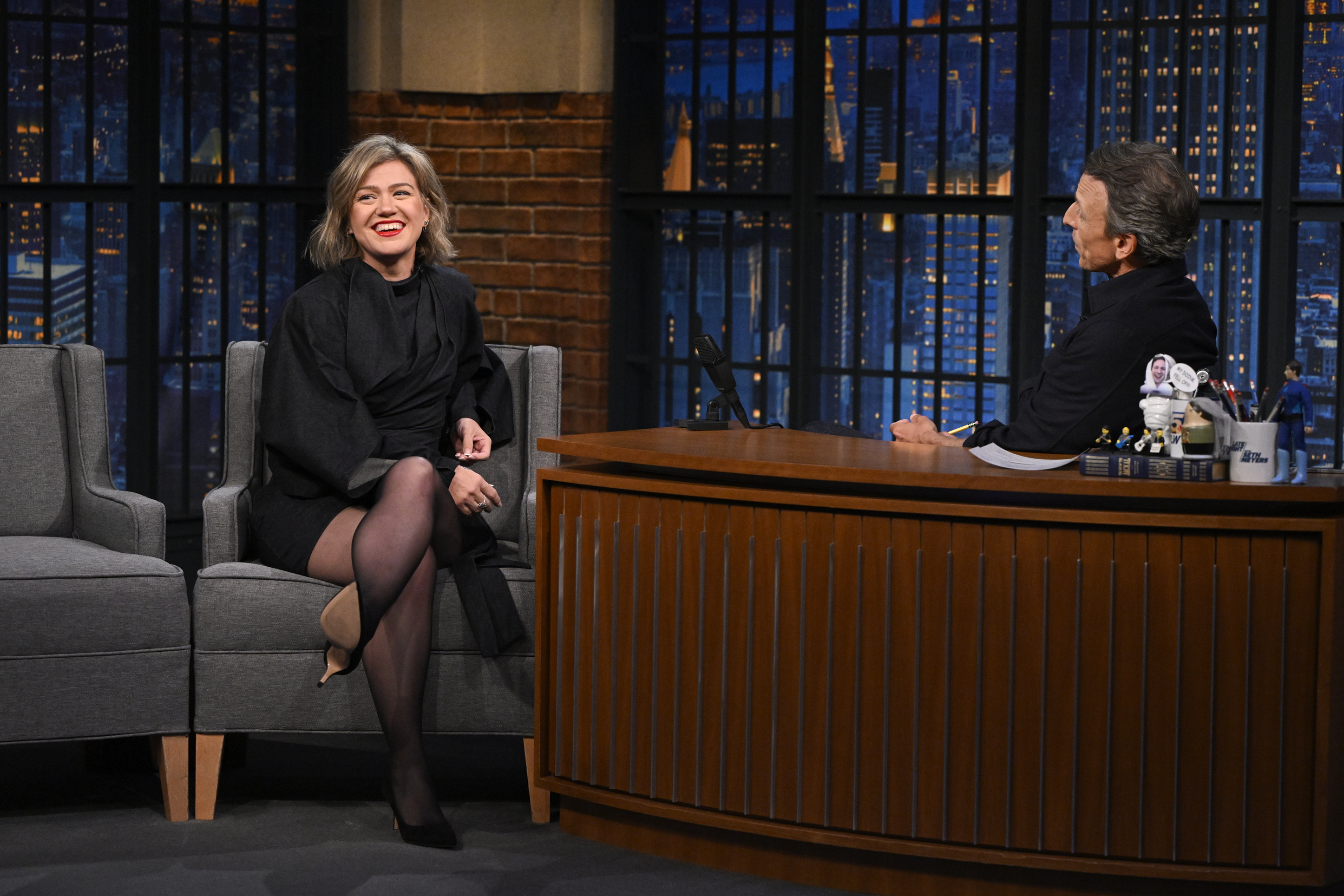 Kelly Clarkson flashed a radiant smile while seated across from host Seth Meyers during Episode 1827 of "Late Night with Seth Meyers" on September 21, 2026, showing off her windswept, layered short bob paired with an elegant draped black minidress, sheer tights, and classic pointed pumps. | Source: Getty Images