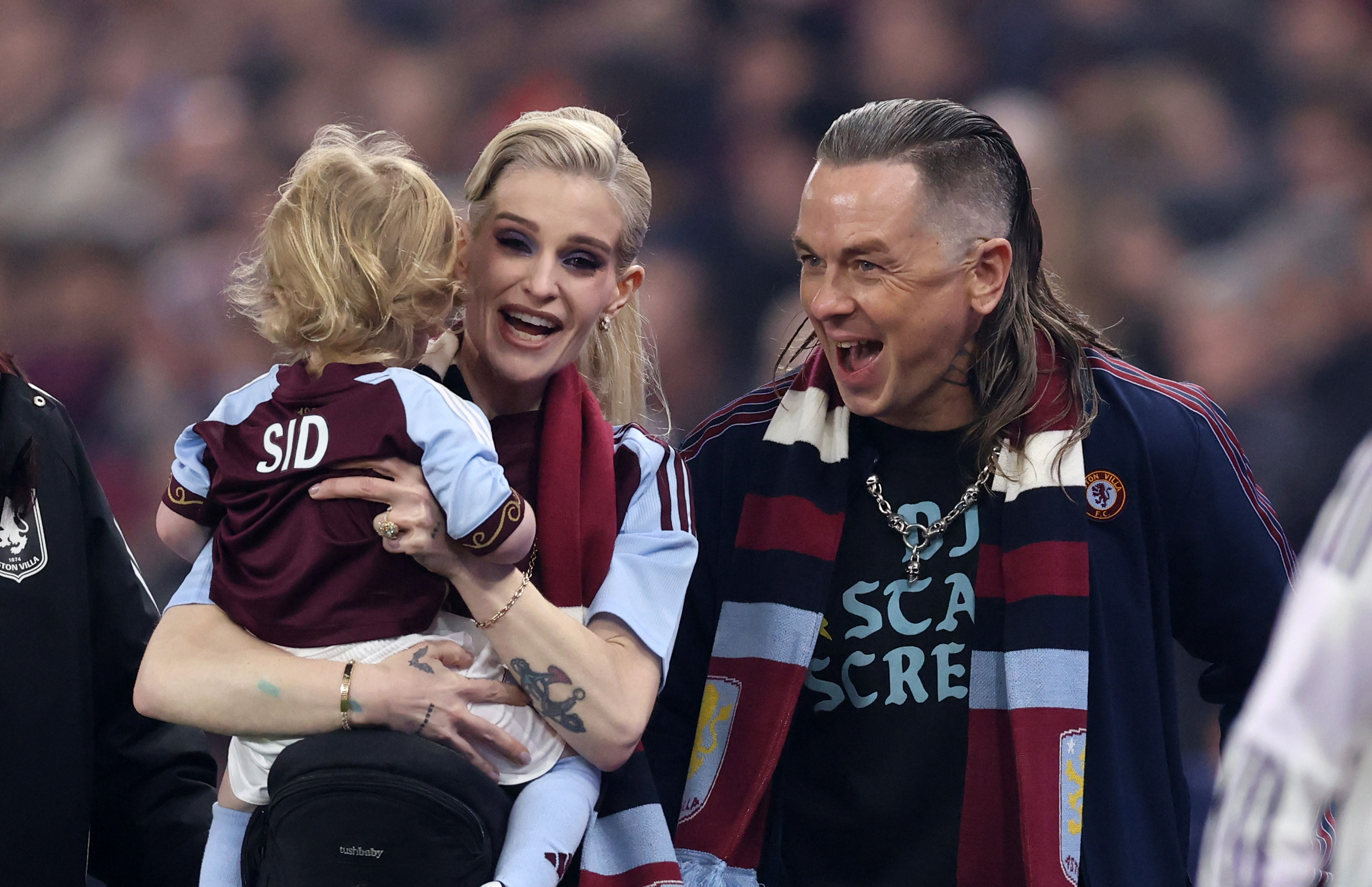 Kelly Osbourne smiled as she held her son Sidney, dressed in a personalized Aston Villa jersey, while Sid Wilson stood beside them during a family outing to a football match in December 2025. | Source: Getty Images