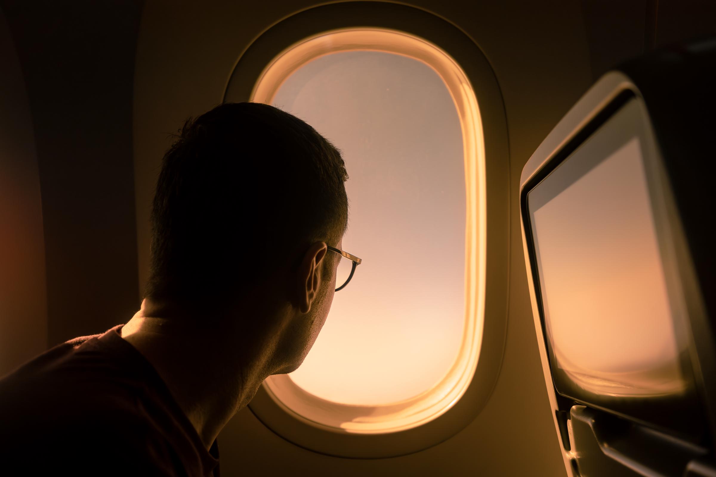 A man looking through a passenger window in a plane | Source: Getty Images