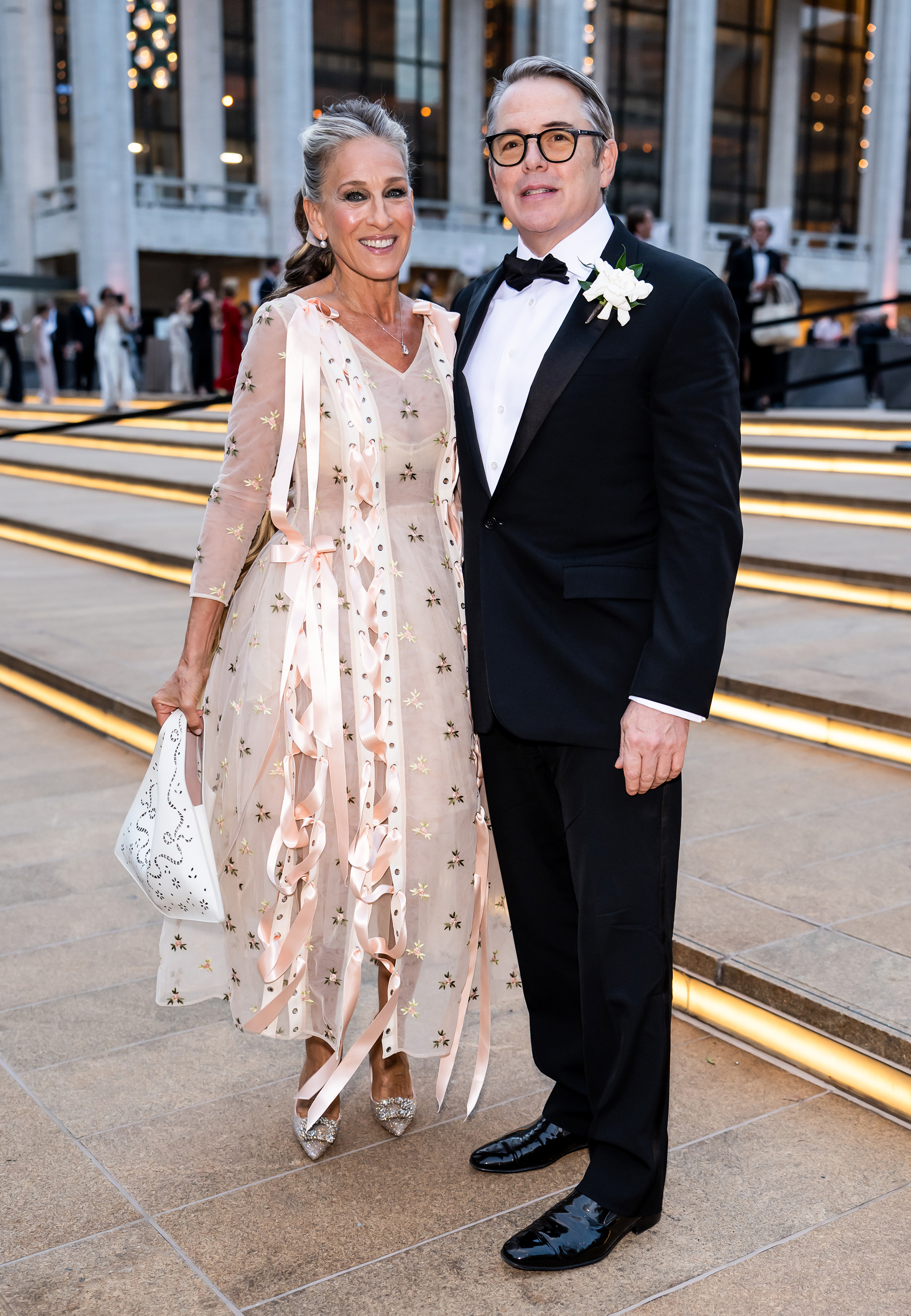 Parker and Broderick pose outside Lincoln Center, where the contrast is striking: her delicate embroidered design against his classic black tuxedo and white boutonniere. | Source: Getty Images