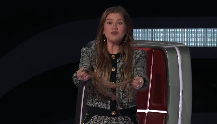 In a clip from "The Voice" highlighted on "Late Night with Seth Meyers" on September 21, 2026, Kelly Clarkson jokingly held out her own clip-on hair extension straight from her red coach's chair to offer it to a contestant, looking playful in a tailored tweed jacket adorned with gold buttons. | Source: YouTube/Late Night with Seth Meyers
