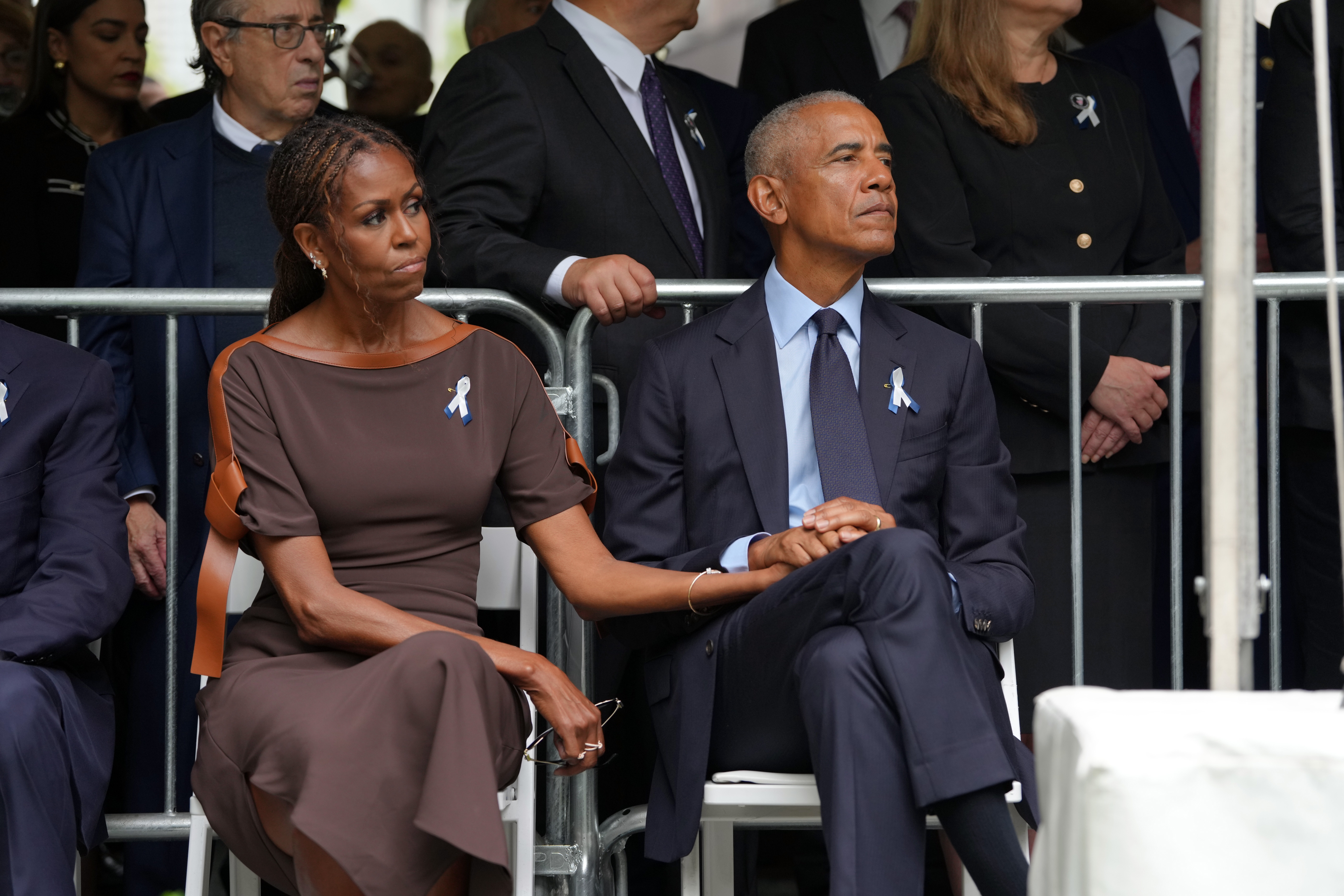 Michelle rests her hand on Barack’s as they sit together during a public ceremony, a quiet gesture of affection that contrasts with the months of speculation surrounding their marriage. | Source: Getty Images
