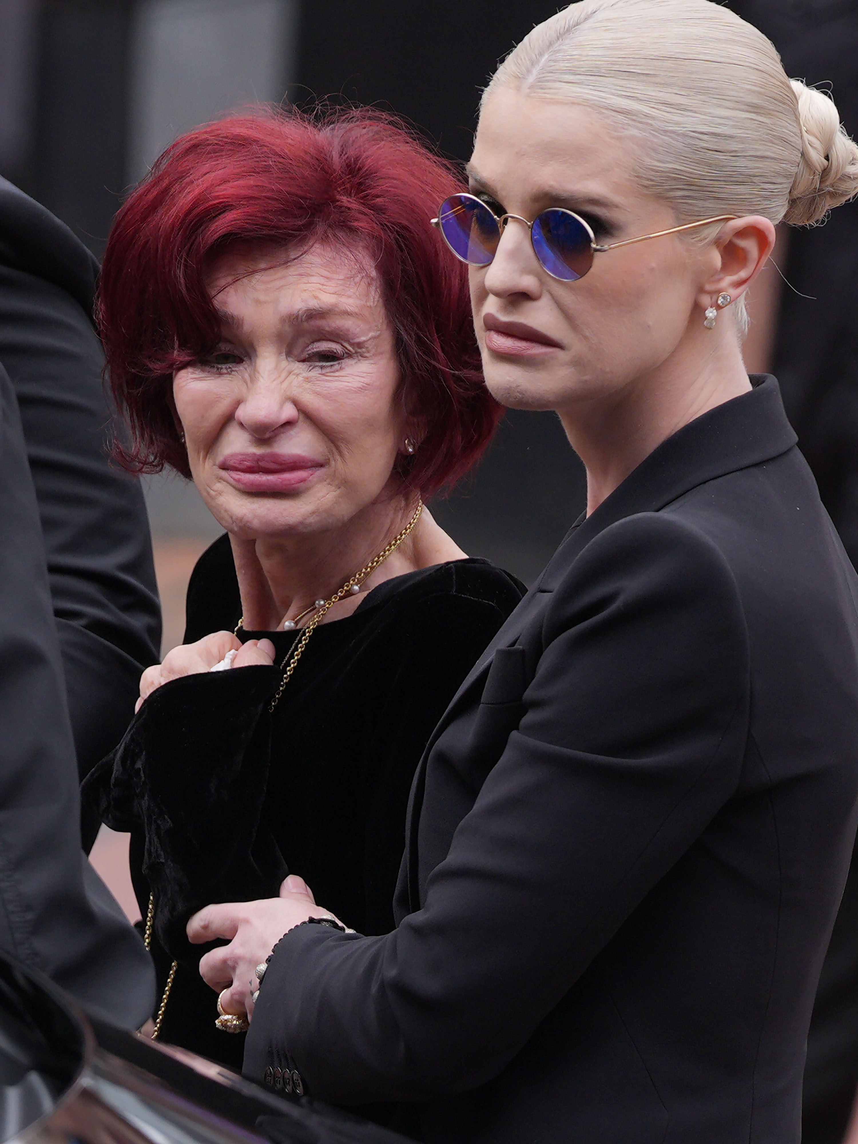 Kelly Osbourne held her visibly emotional mother, Sharon, close as they mourned Ozzy Osbourne in Birmingham on July 30, 2025, just eight days after his death. | Source: Getty Images.