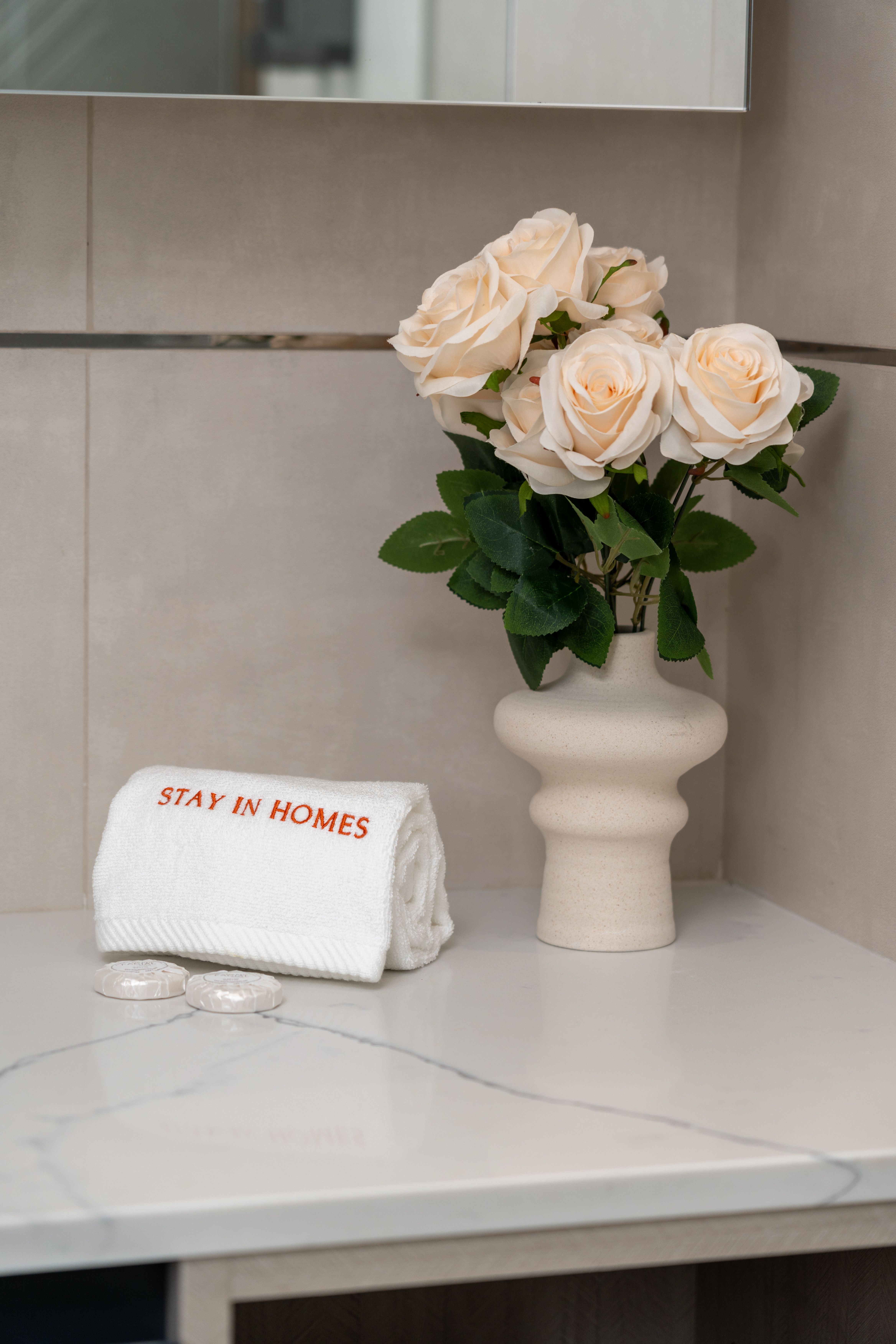 A vase of white roses sits beside neatly folded towels on a bathroom counter. | Source: Pexels