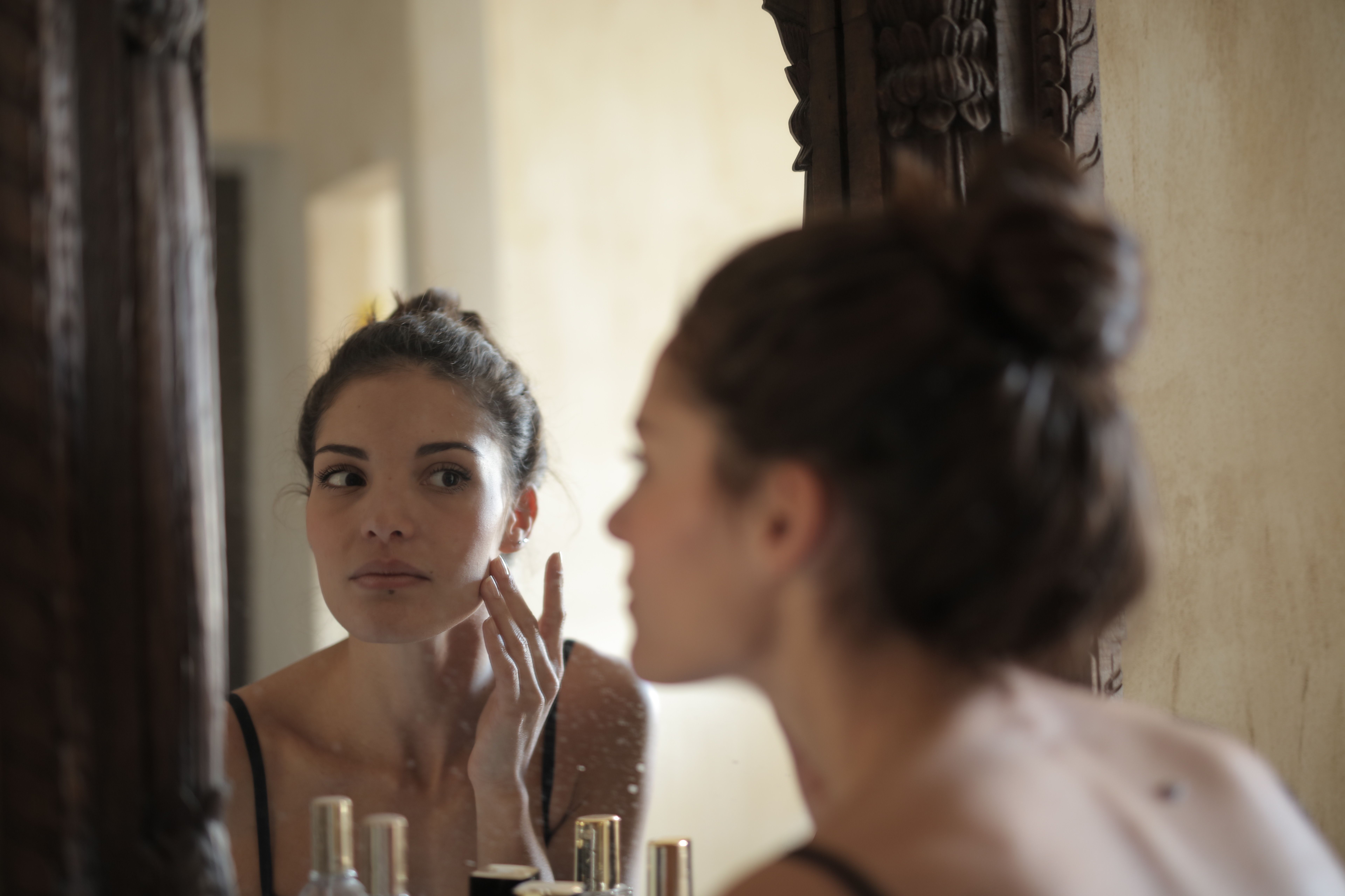 Woman observing her face in front of a mirror | Source: Pexels