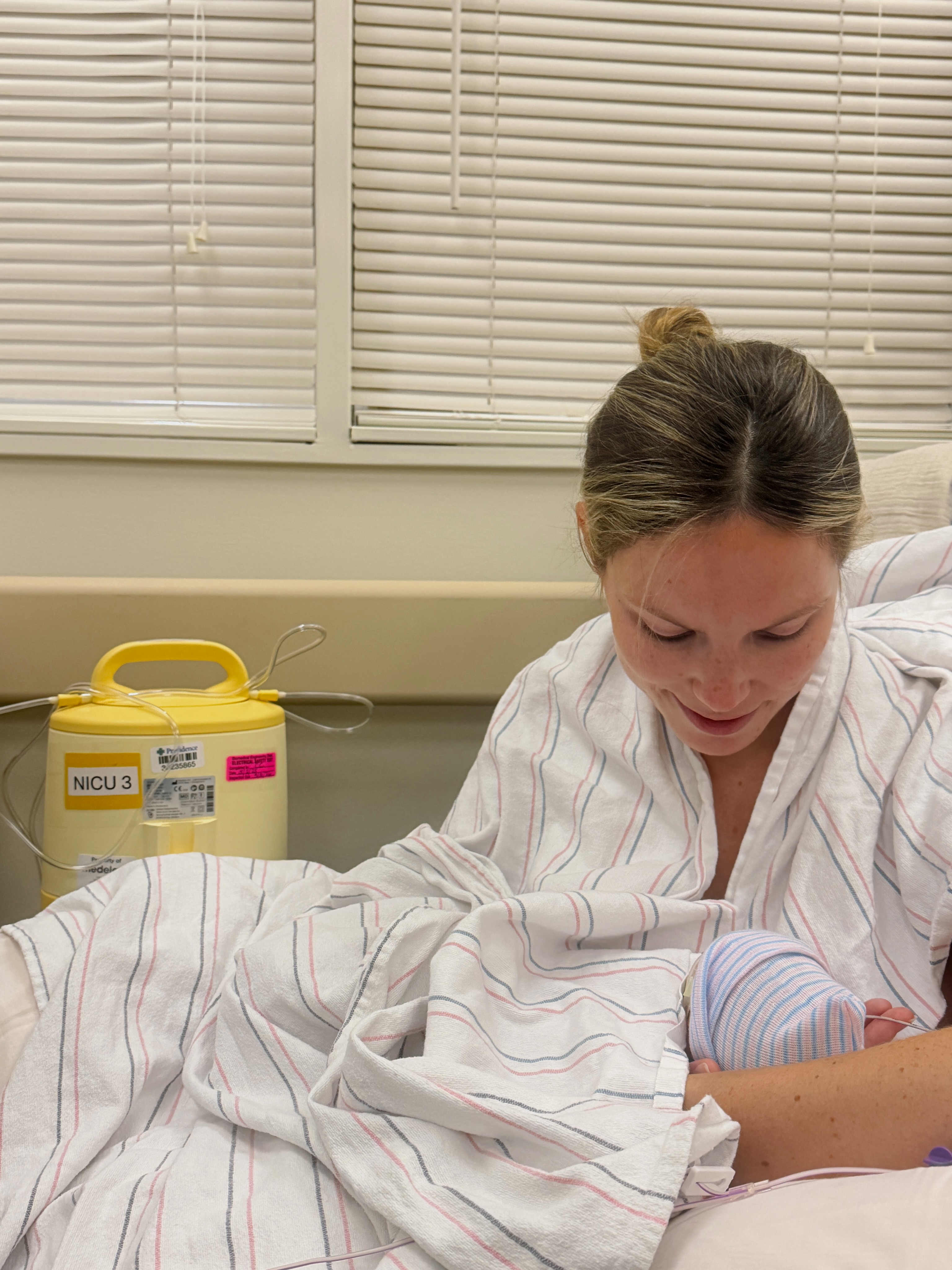 Elliott Bure looks down at her newborn son, Bond, while holding him against her in the hospital following his premature arrival. | Source: Instagram/elliottpbure
