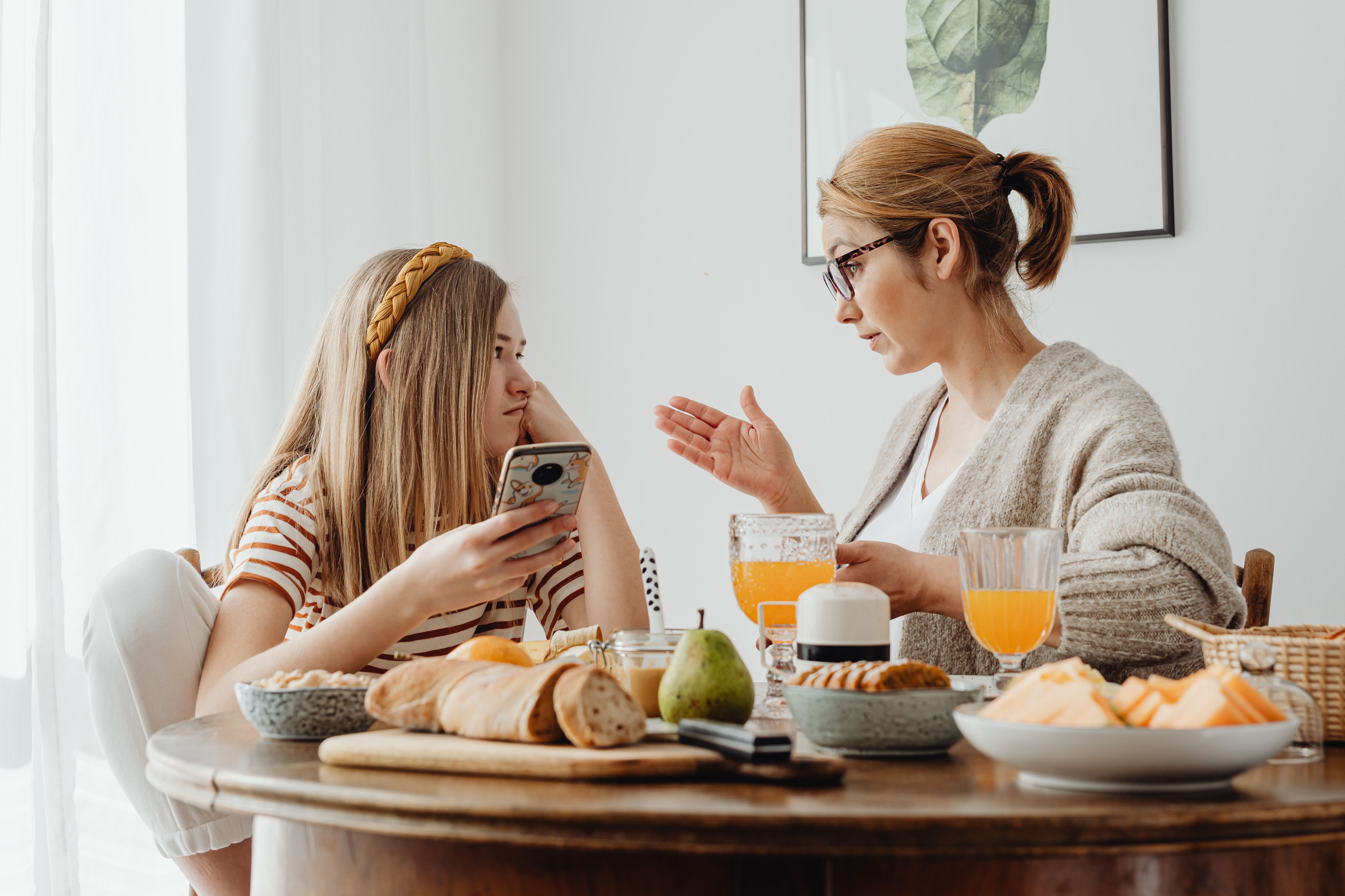 A mother gesturing to her teen daughter over breakfast | Source: Pexels