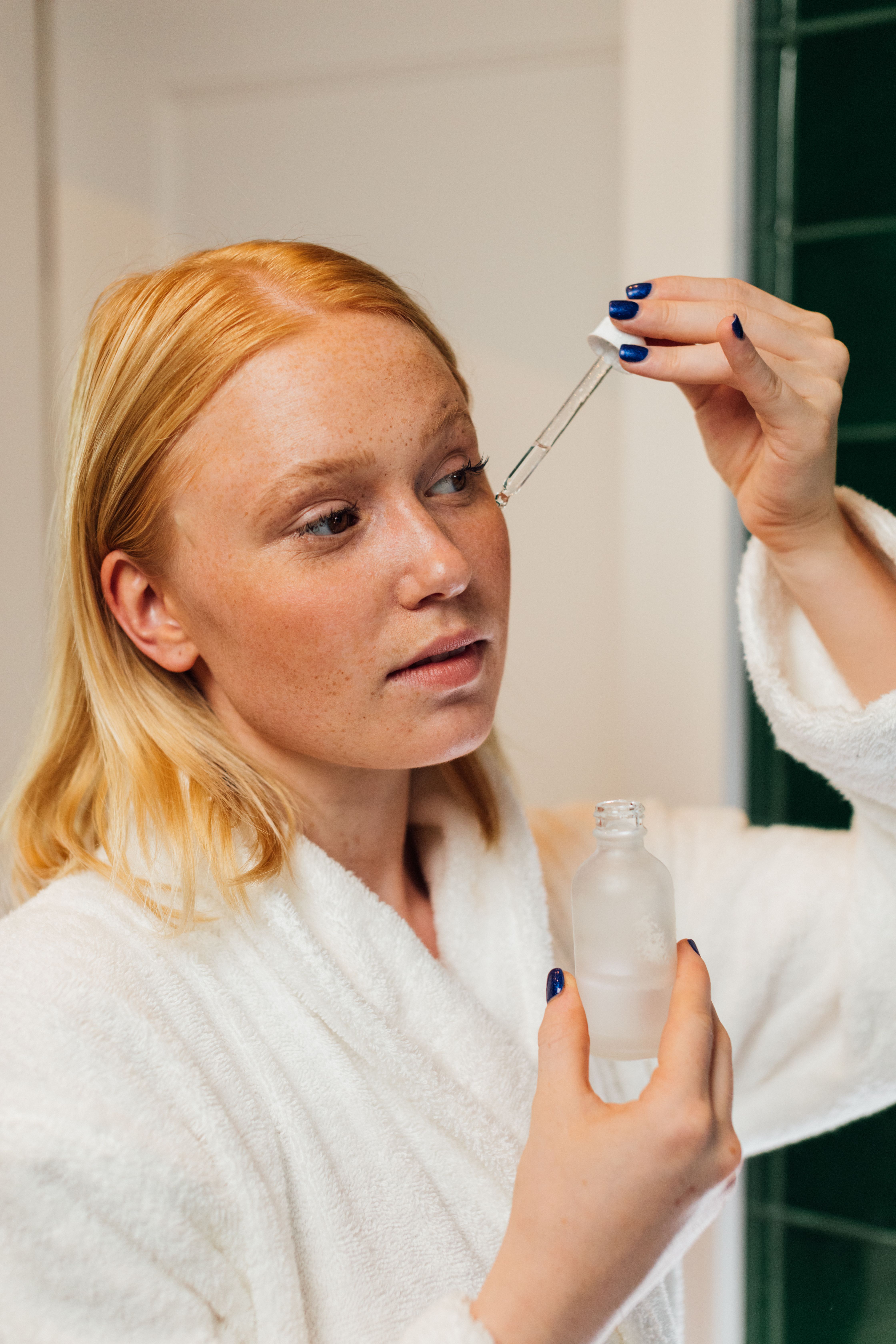 A woman applying a serum to her face | Source: Pexels