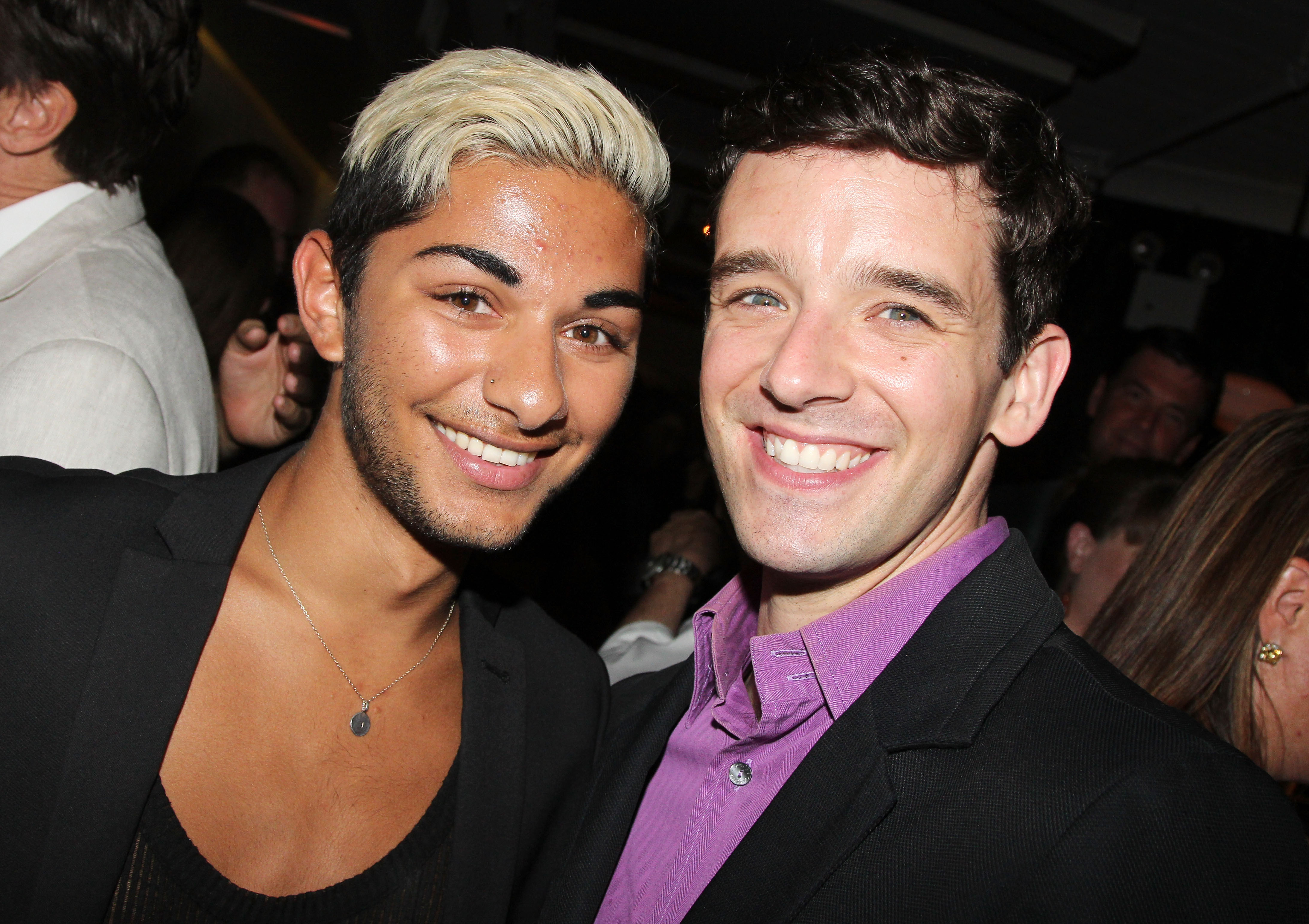 Mark Indelicato reunites with former "Ugly Betty" co-star Michael Urie at the opening night celebration for Urie's solo show "Buyer & Cellar" at the Barrow Street Theatre on June 24, 2013, in New York City. Indelicato sports two-tone dark-and-platinum hair, light stubble, a deep-scoop top under a black blazer, and a silver pendant necklace, beaming cheek-to-cheek alongside Urie, who smiles in a vibrant lavender button-up shirt and dark jacket.
