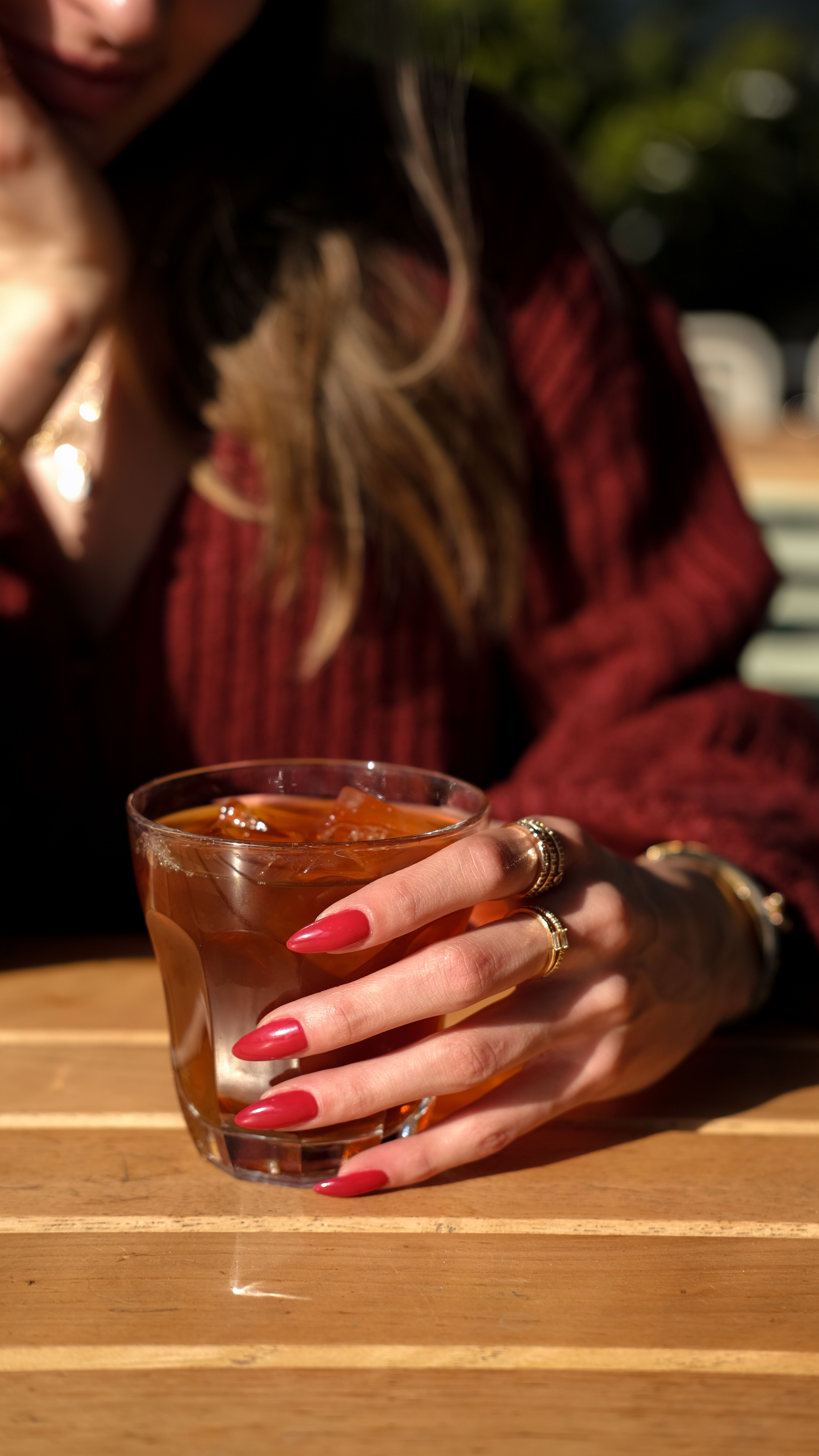 Woman with red manicure holding a drink | Source: Pexels