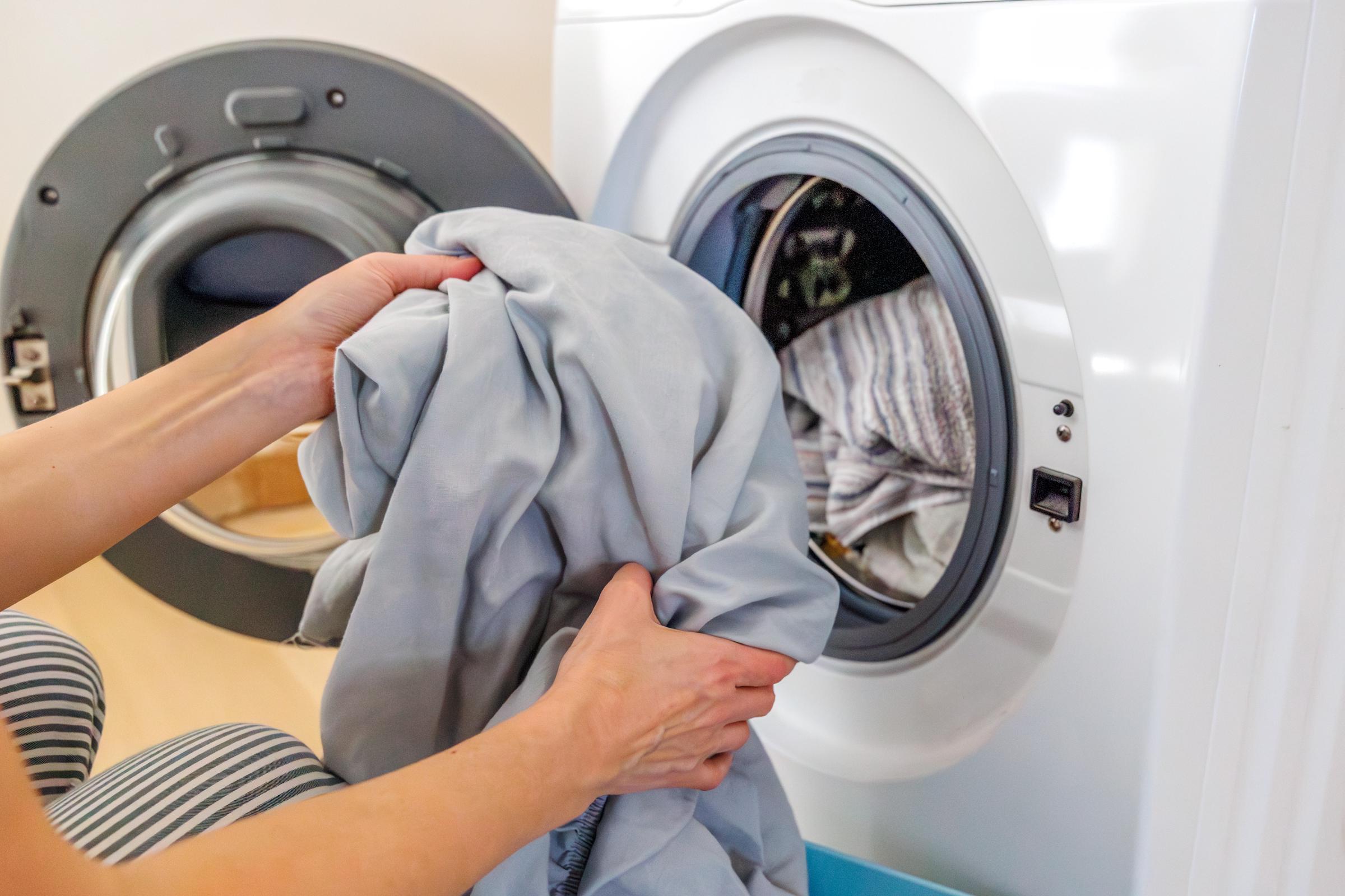 A woman loading laundry into a washing machine | Source: Getty Images