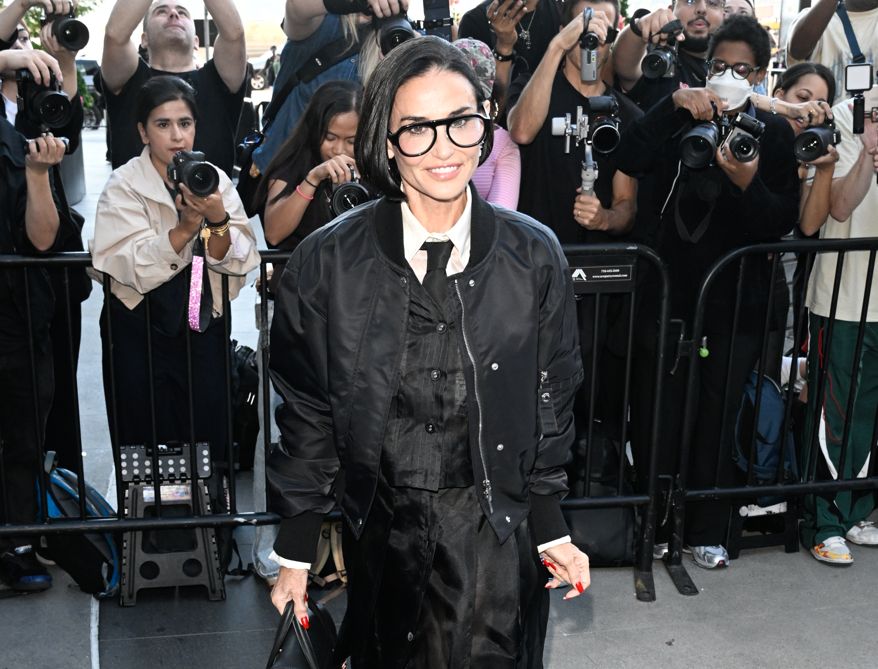 Demi Moore puts her chin-length bob front and center as she poses for photographers, pairing the glossy style with oversized black glasses and layered Thom Browne separates. | Source: Getty Images