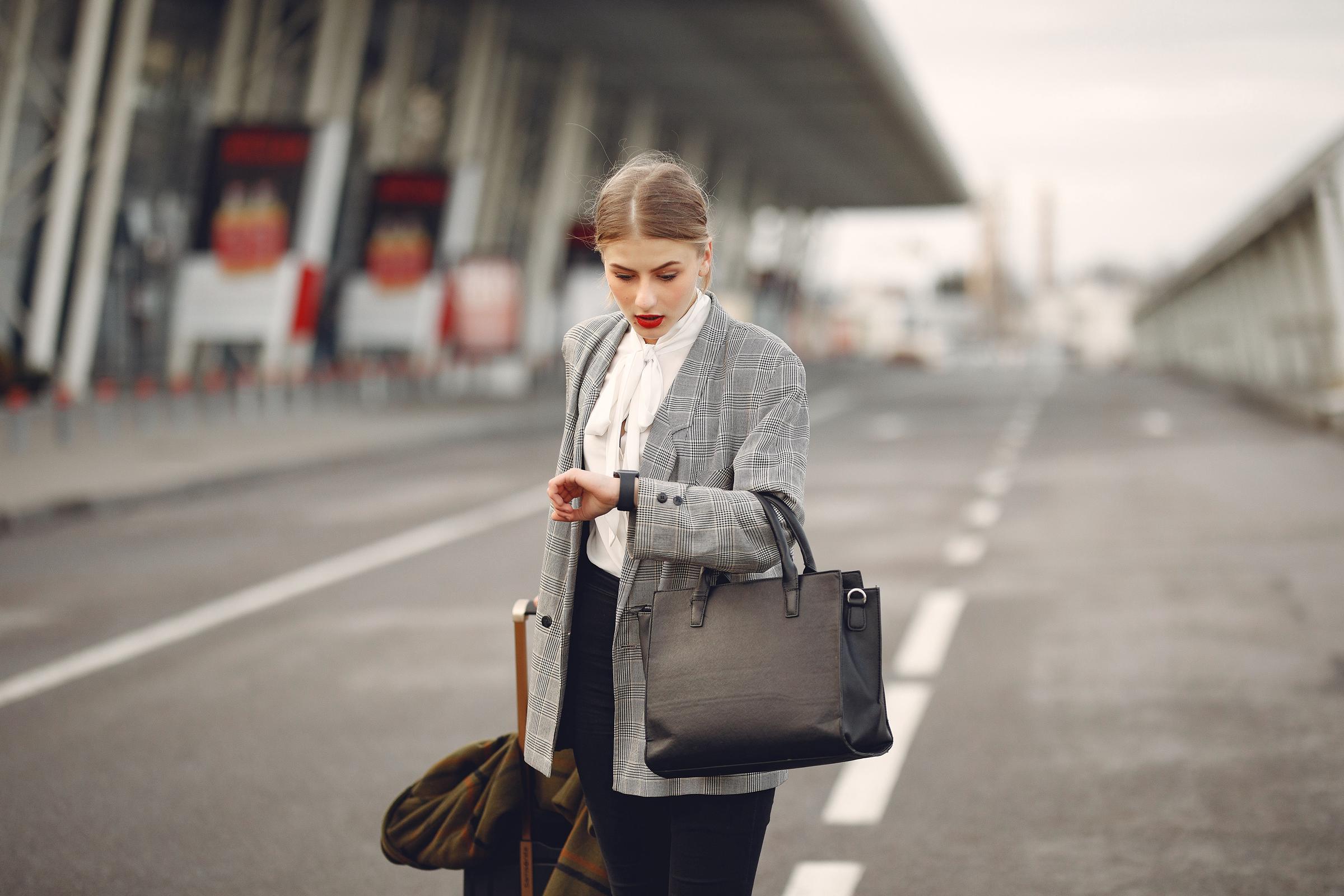 A woman checking her watch while waiting at an airport terminal | Source: Pexels