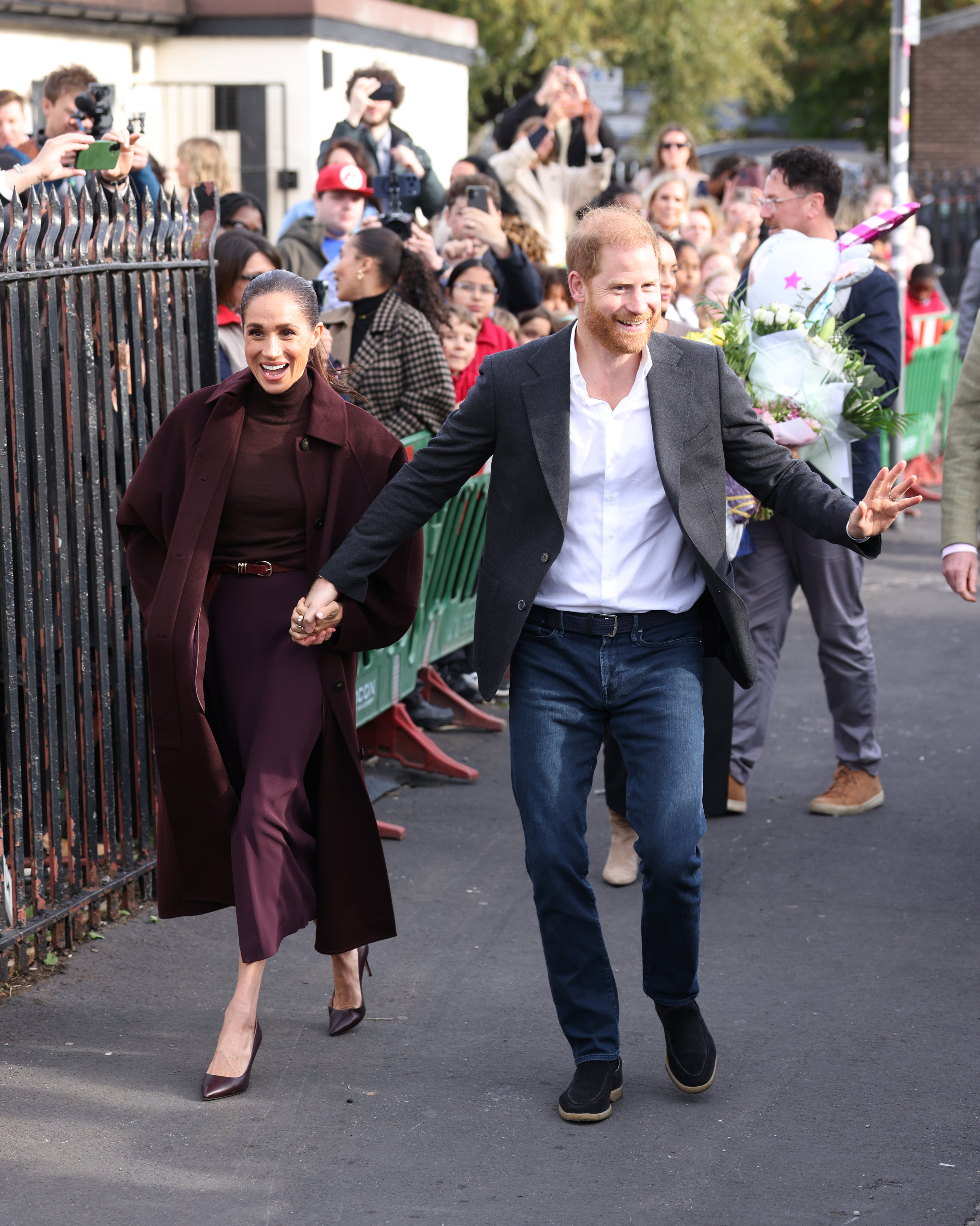 Harry adopted a distinctly protective stance, repeatedly wrapping an arm around Meghan's shoulder to steady her and holding her hand as they navigated the crowds. | Source: Getty Images