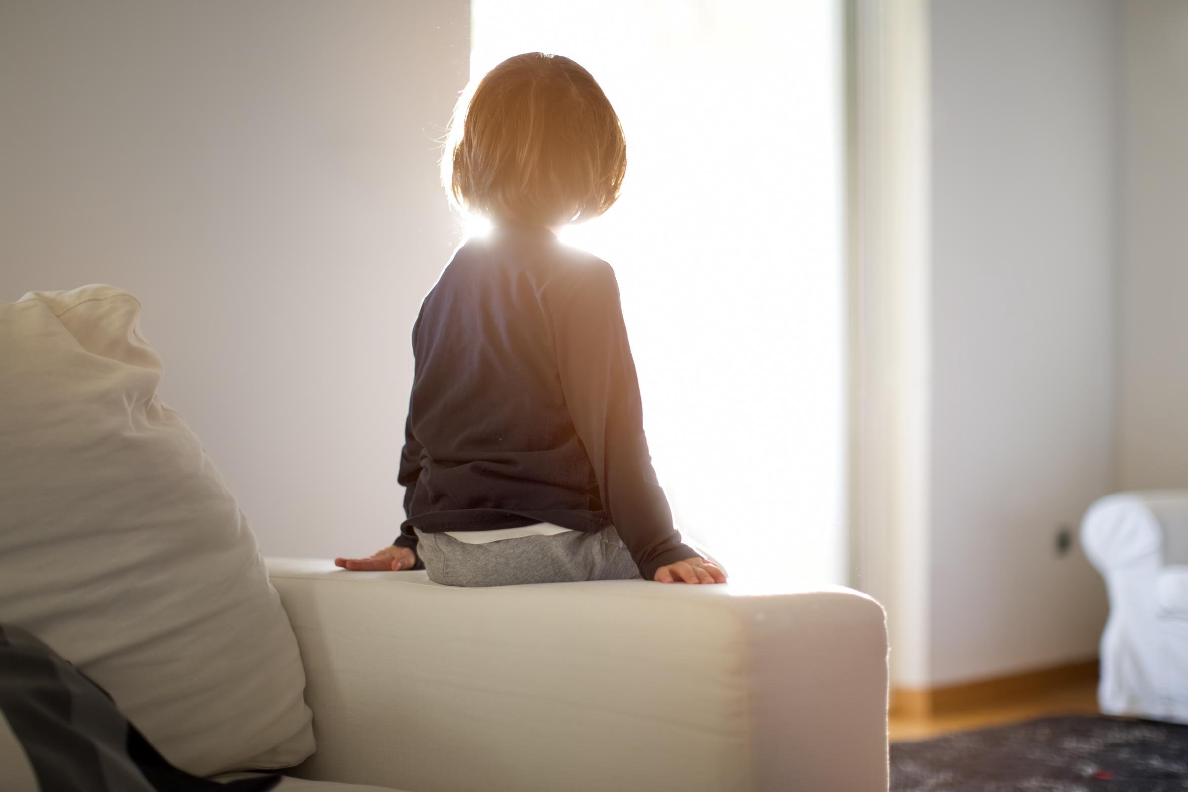 A small boy sitting on the armrest of a couch | Source: Getty Images