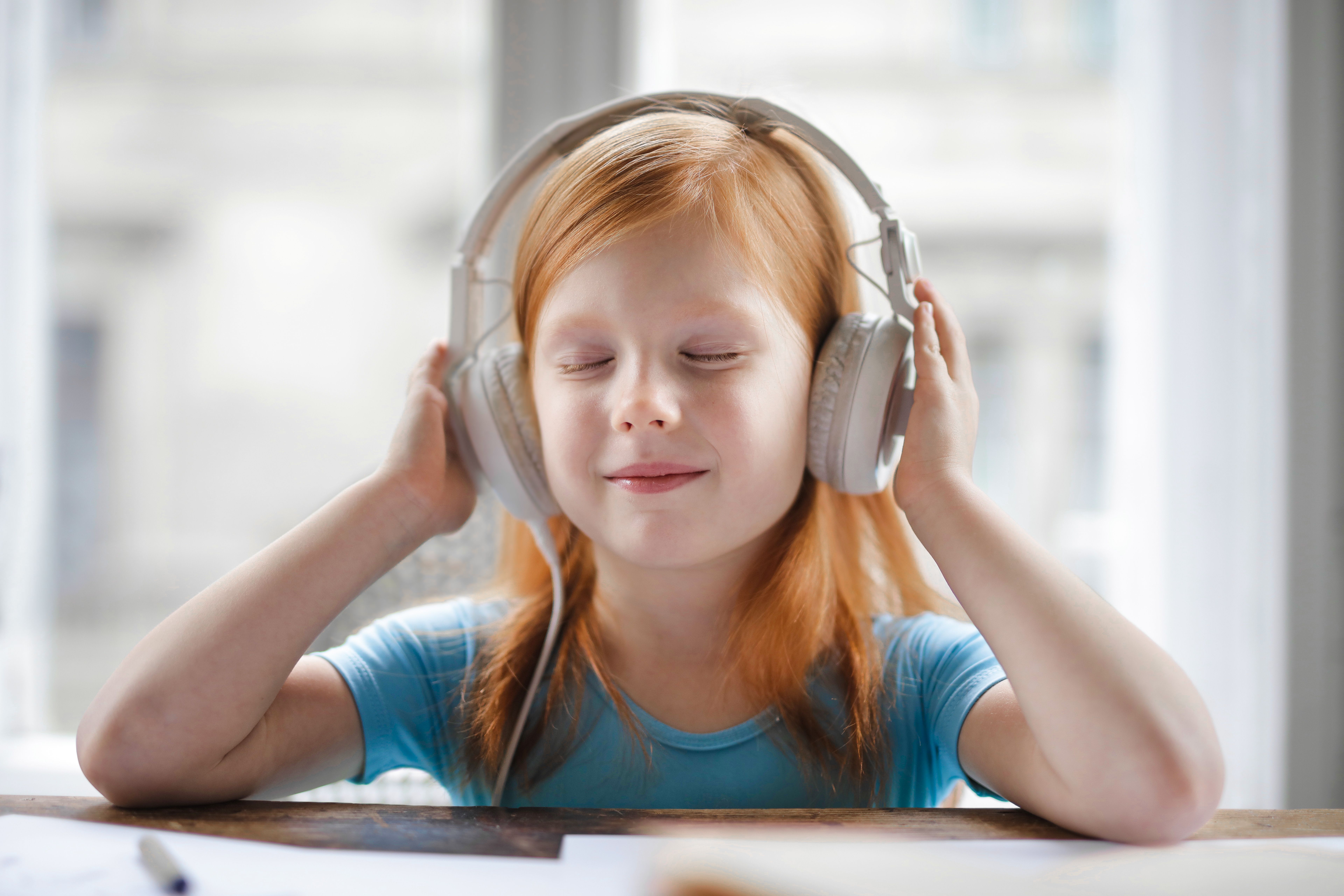 A smiling little girl listening to music with her eyes closed | Source: Pexels
