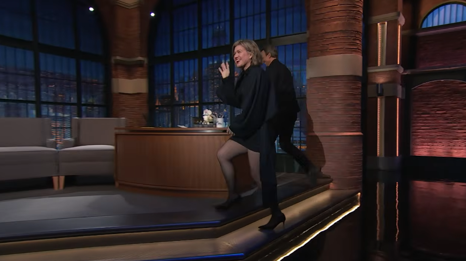 Kelly Clarkson waved to the audience as she stepped down toward the interview chair on "Late Night with Seth Meyers" on September 21, 2026, debuting her modern short bob paired with a stylish draped black minidress, sheer tights, and pointed pumps. | Source: YouTube/Late Night with Seth Meyers