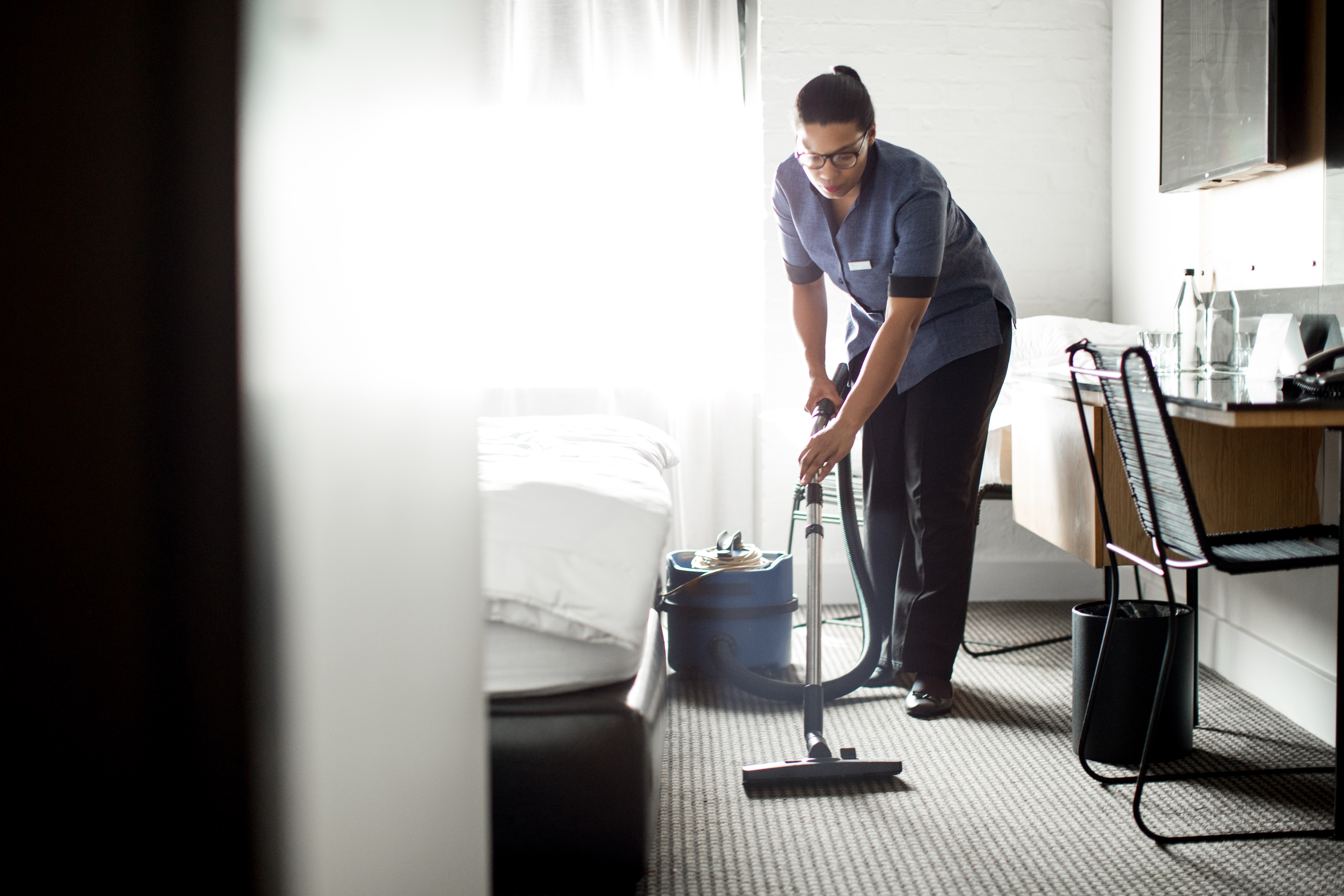A housekeeper vacuuming a hotel room | Source: Getty Images