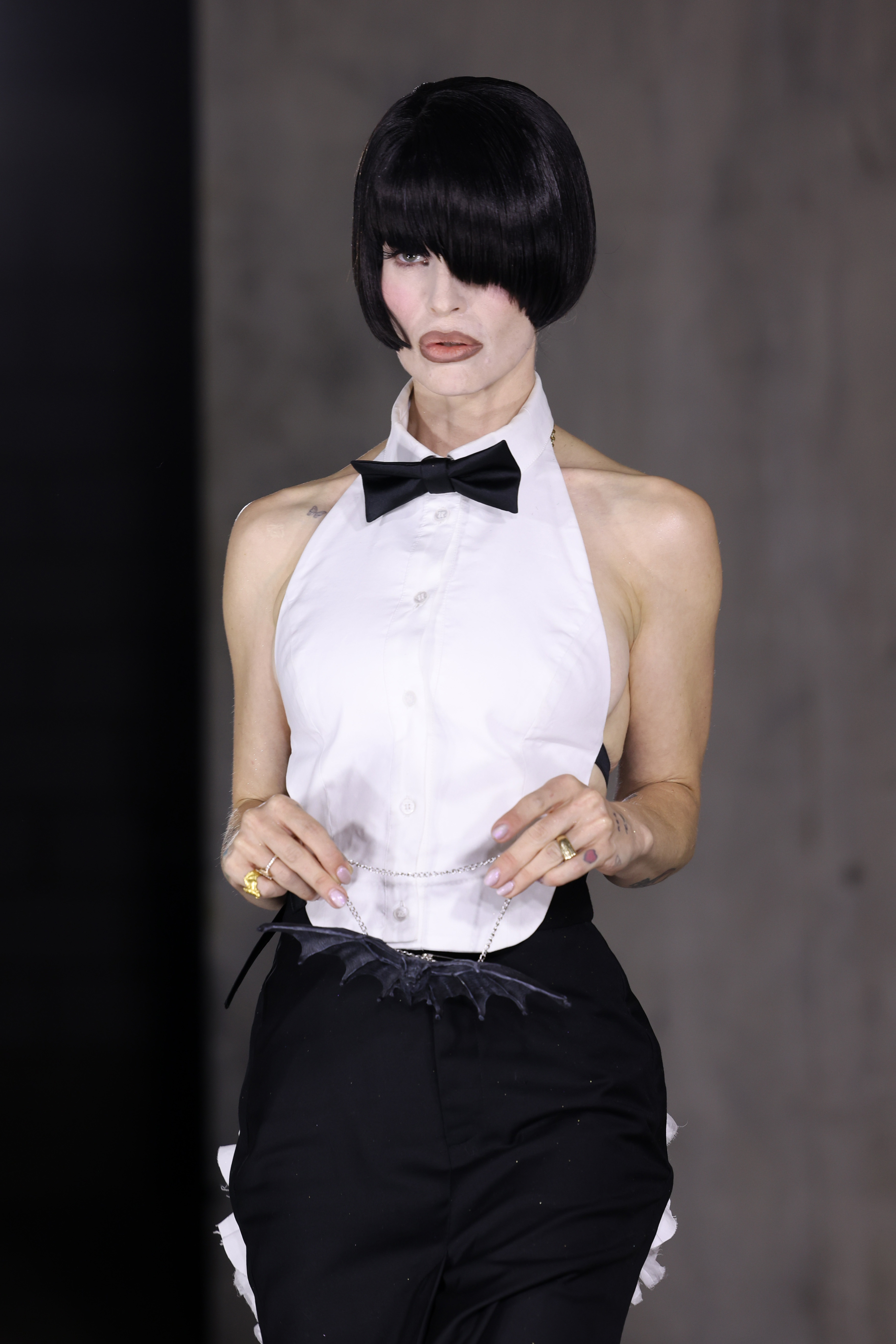 Kelly Osbourne showed off a dramatic new look with a jet-black bob covering one eye, wearing a white halter-style shirt, black bow tie, and tailored trousers, with a bat-shaped accessory recalling her father Ozzy's famous rock legacy. | Source: Getty Images.