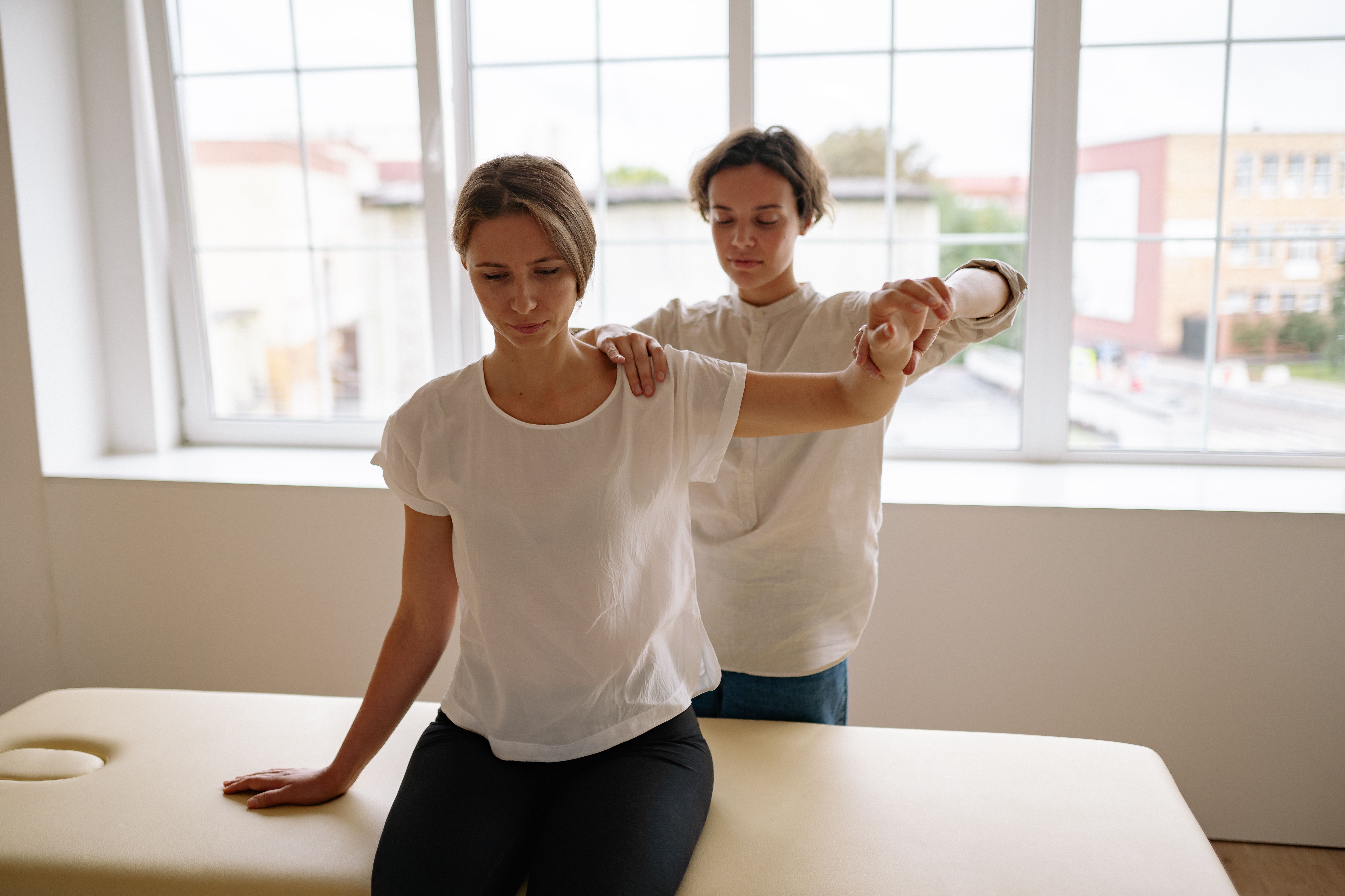 Woman rehabilitating her shoulder with the help of a therapist | Source: Pexels