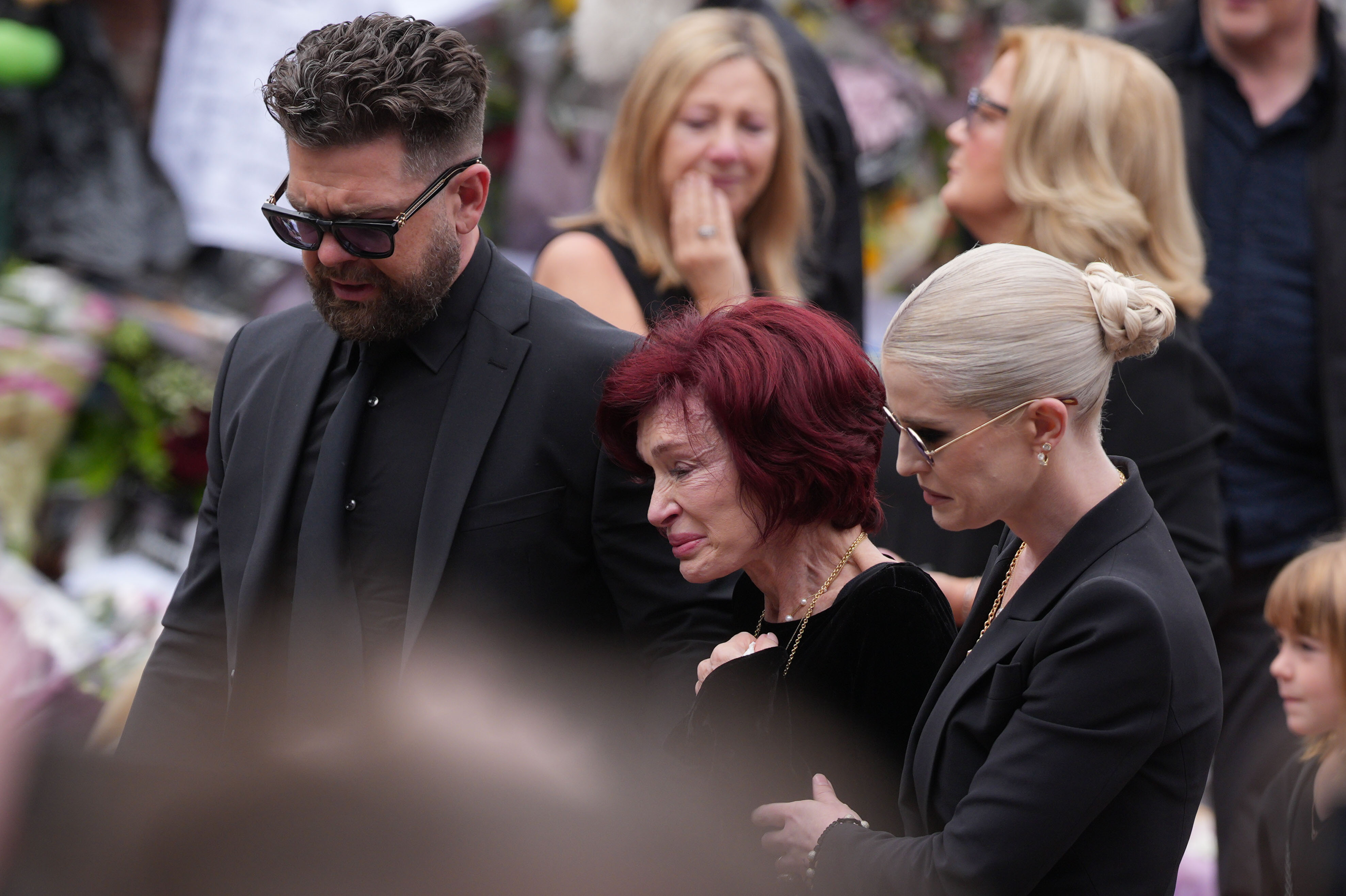 Jack and Kelly Osbourne stood close to their visibly emotional mother, Sharon, as the family gathered in Birmingham on July 30, 2025, to say their final goodbye to Ozzy Osbourne. | Source: Getty Images.