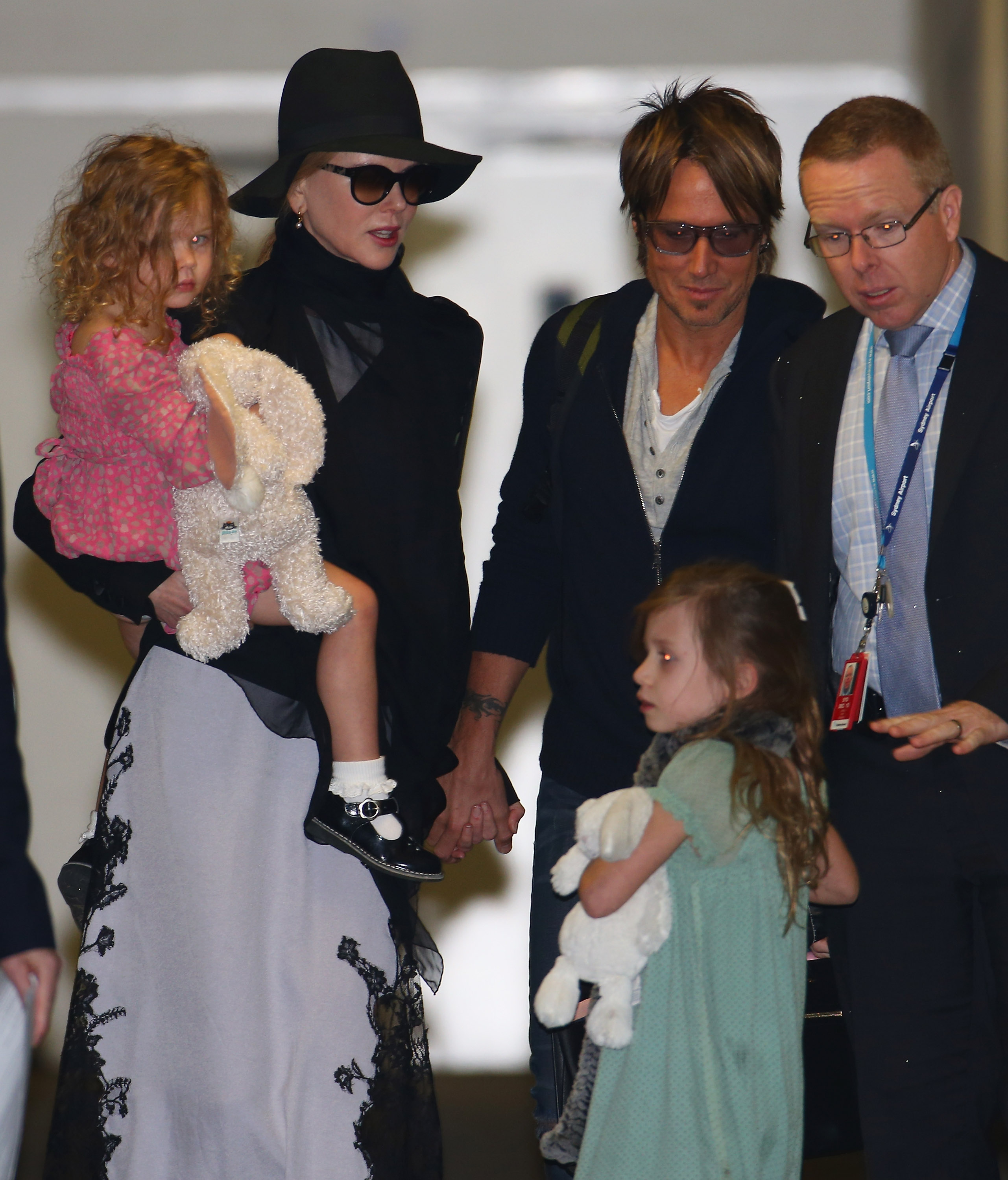 Nicole Kidman carries three-year-old Faith Margaret while Keith Urban holds five-year-old Sunday Rose’s hand at Los Angeles International Airport in January 2014. Both girls brought their favorite stuffed animals along for the family trip. | Source: Getty Images